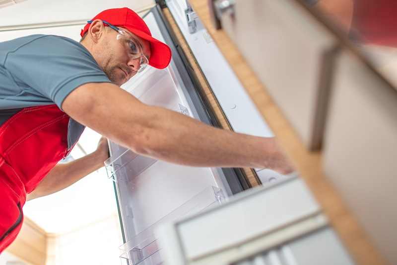 rv technician looking inside camper refrigerator KJXNGDJ compressed